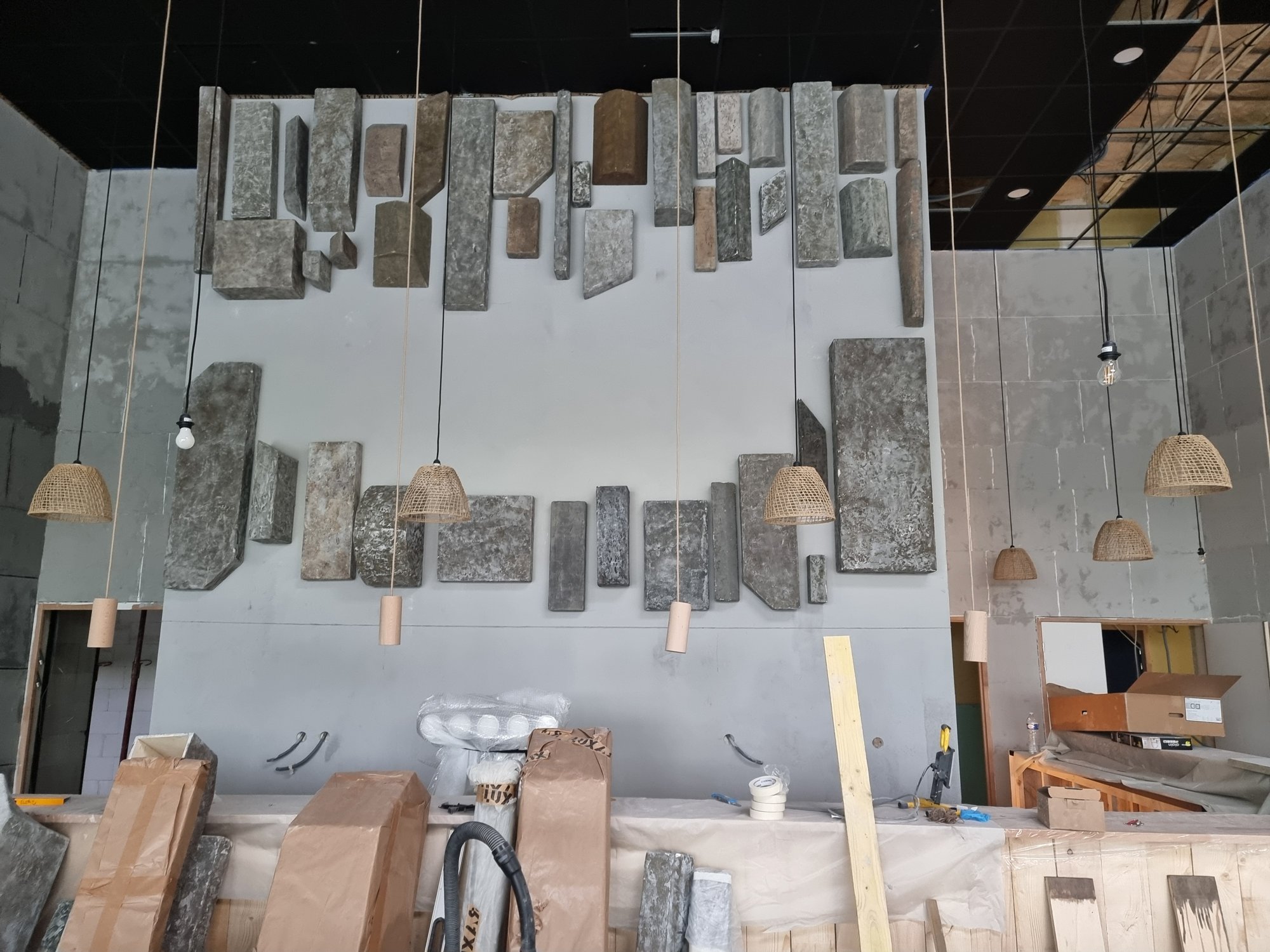Le mur de panneaux suspendus et ses suspensions, en cours de pose