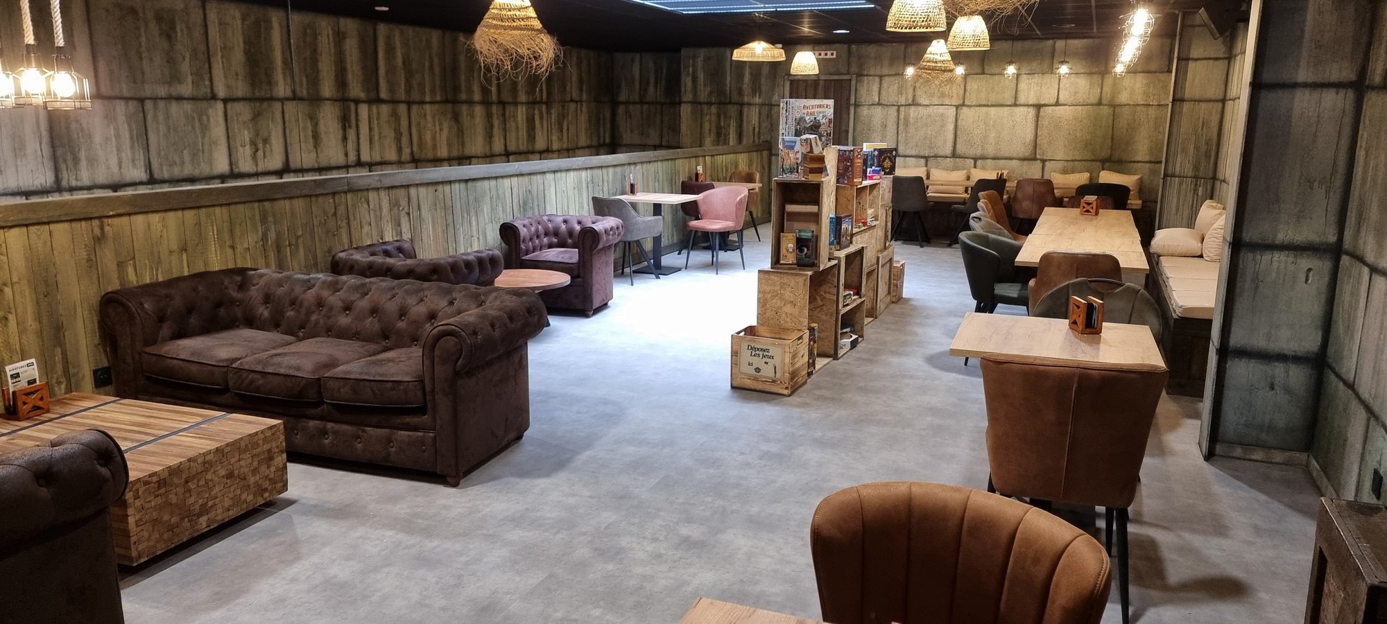 Le salon du bar à jeux, canapés et caisses de jeux de société