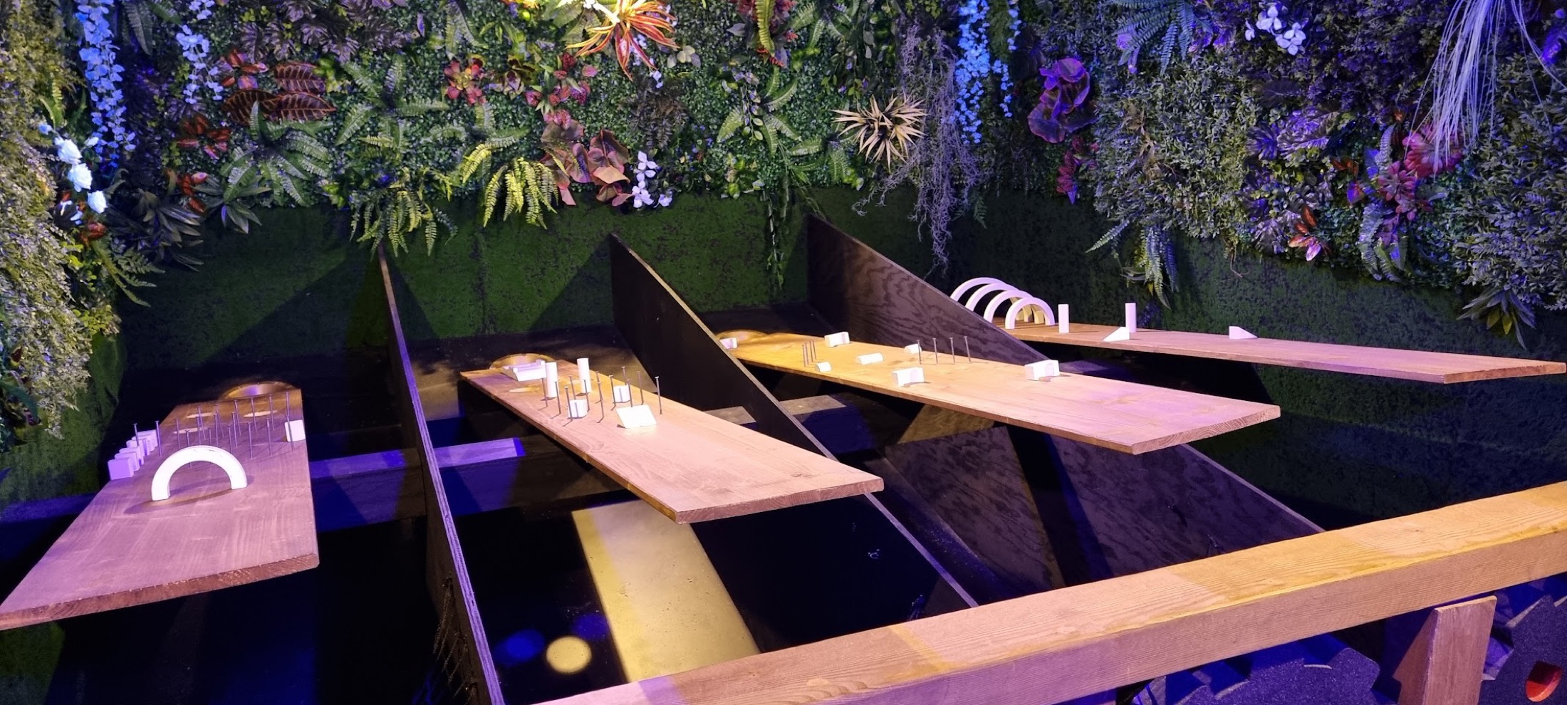 Une salle de jeu du Temple, plateaux de bois et mur végétal éclairé