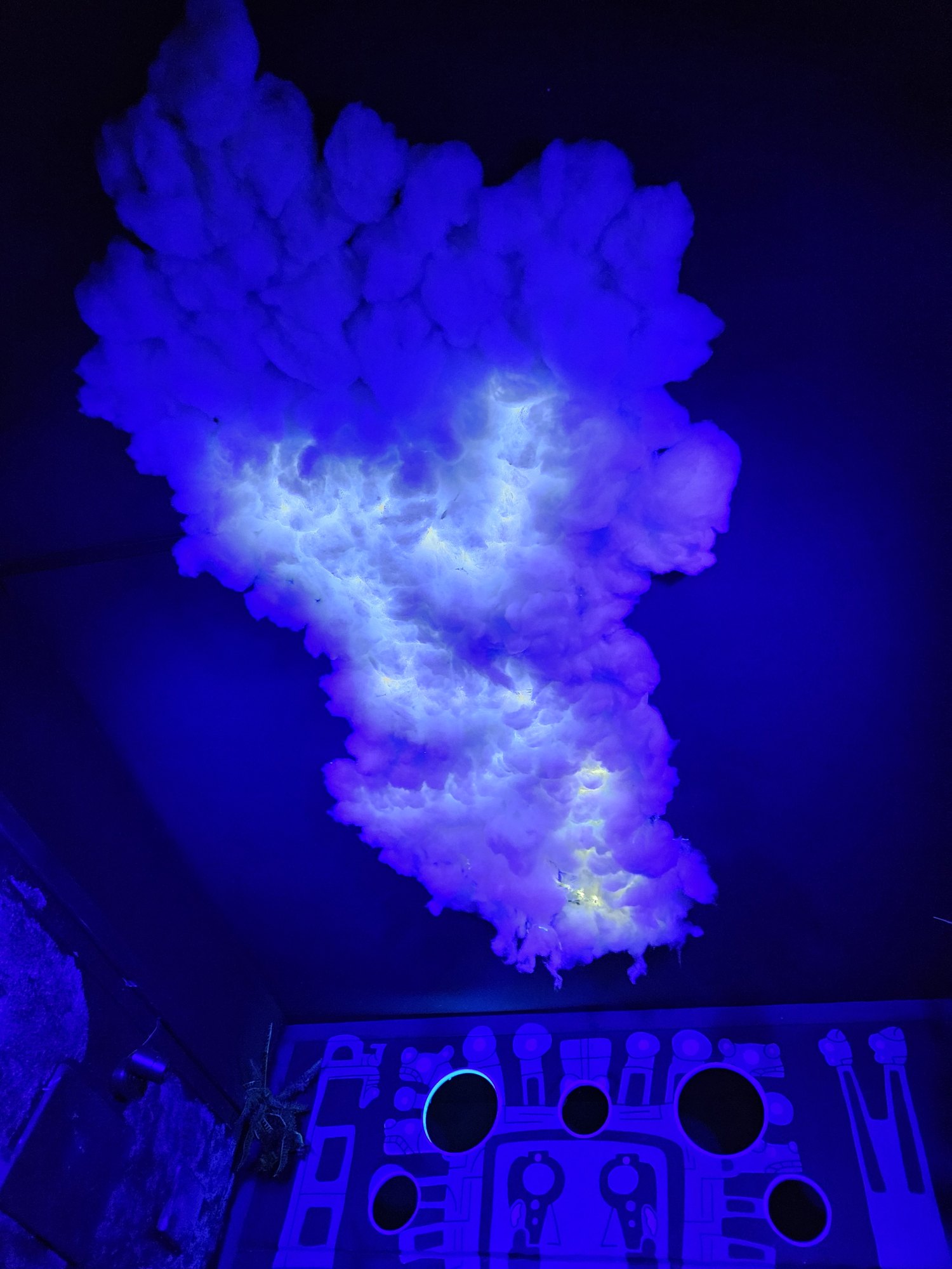 The cloud hung above the play wall, under blacklight