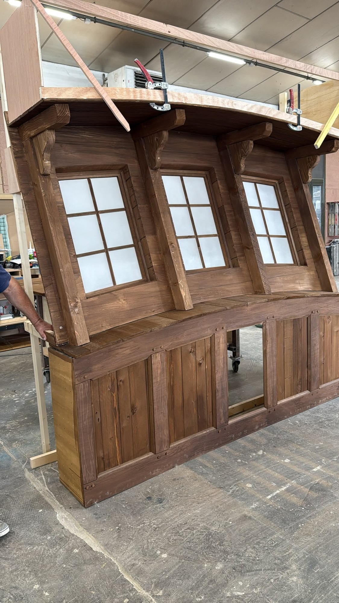 The curved small-pane façade, aged in the workshop